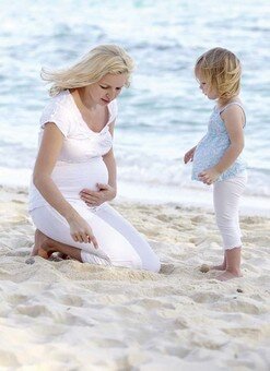 schwangere Frau und Baby am Strand